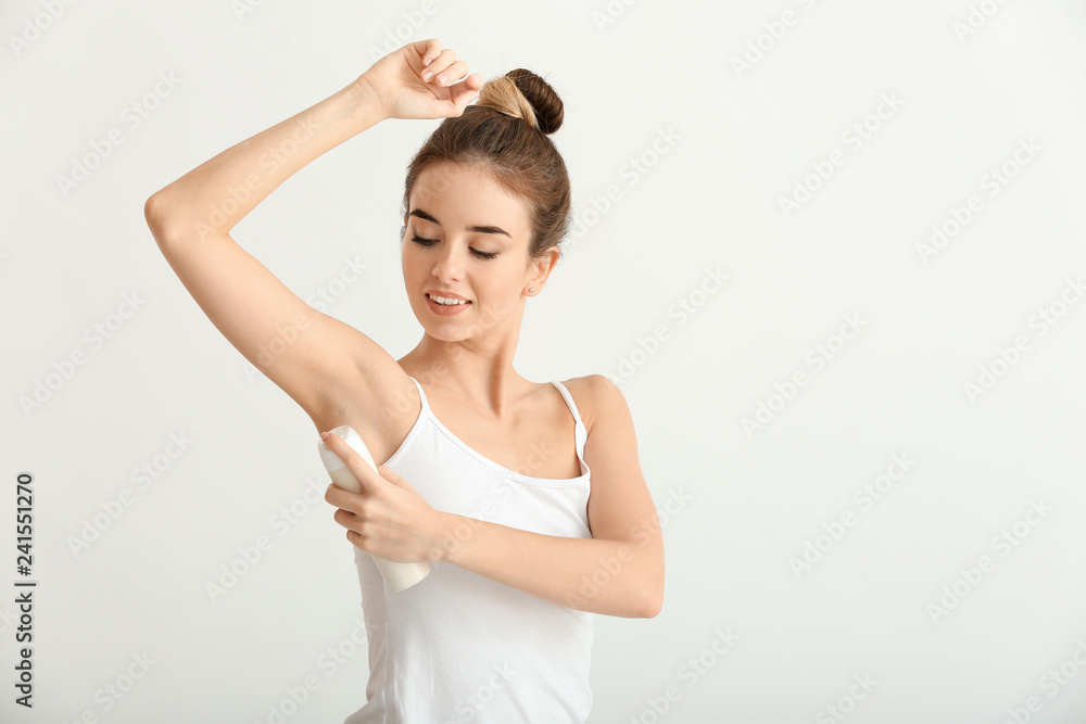 Beautiful young woman with deodorant on light background Beautiful young woman with deodorant on light background