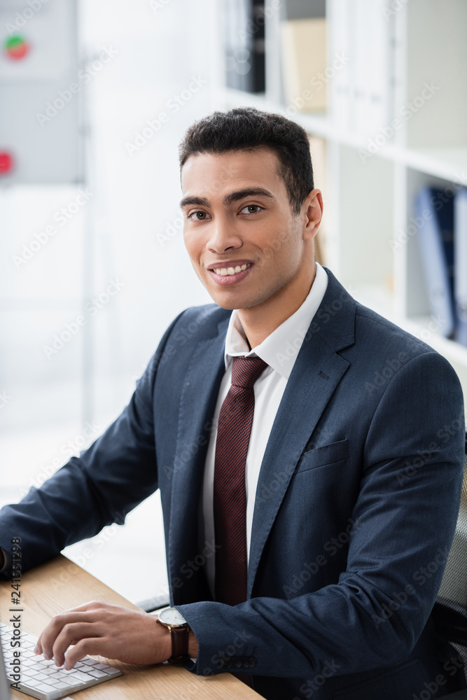 handsome young businessman working with desktop computer and smiling at camera in office handsome young businessman working with desktop computer and smiling at camera in office
