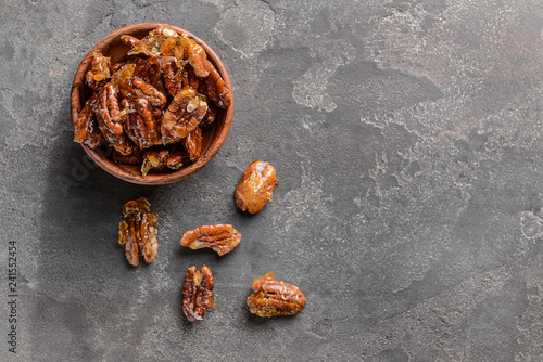 Bowl with candied pecan nuts on grey background © Pixel-Shot