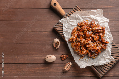 Tasty candied pecan nuts on wooden table