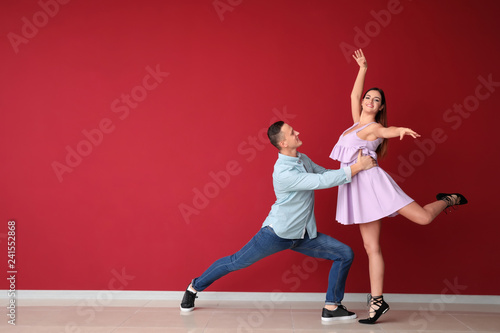 Young couple dancing near color wall
