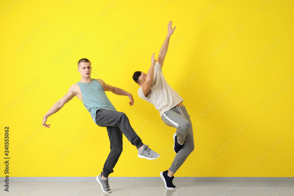 Young men dancing near color wall Young men dancing near color wall