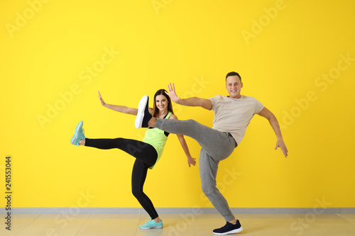 Young couple dancing near color wall