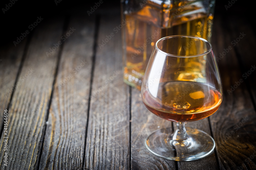 Glass and a bottle of brandy or cognac on the wooden table. Glass and a bottle of brandy or cognac on the wooden table.