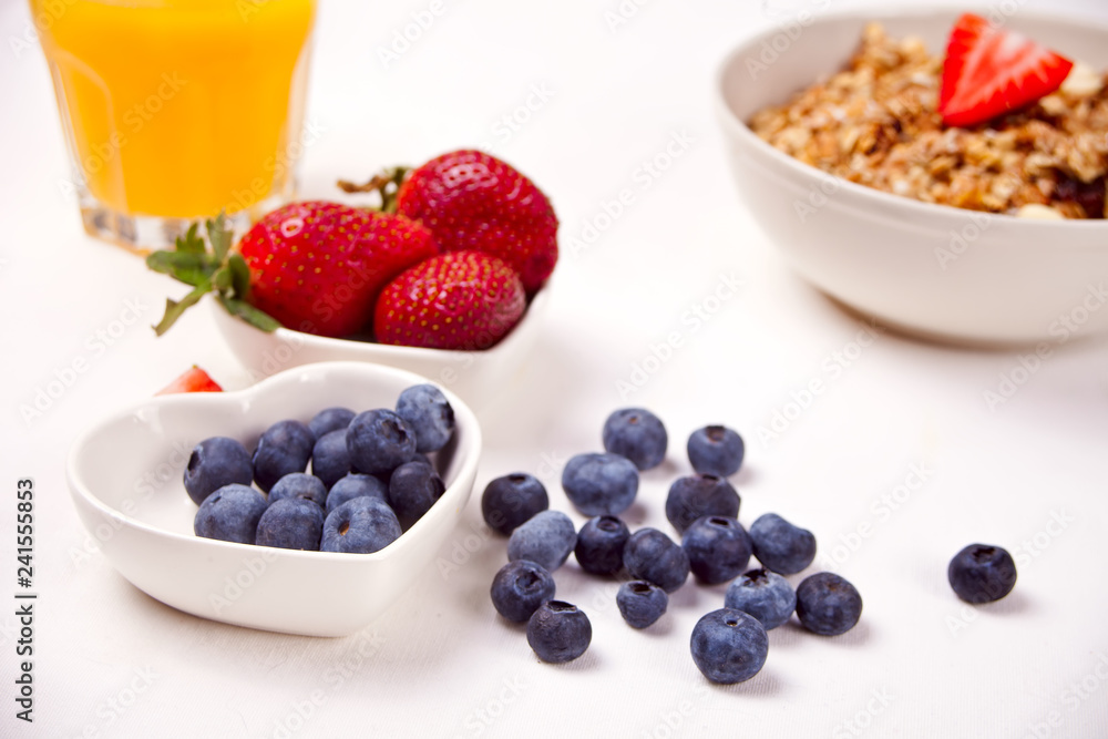 A plate with muesli, bowls with berries on the white table A plate with muesli, bowls with berries on the white table