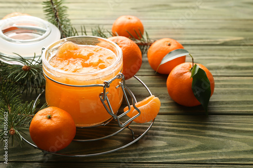 Jar of tasty tangerine jam on wooden table