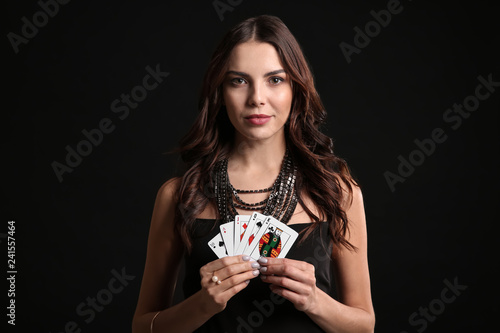 Beautiful young woman with cards on dark background