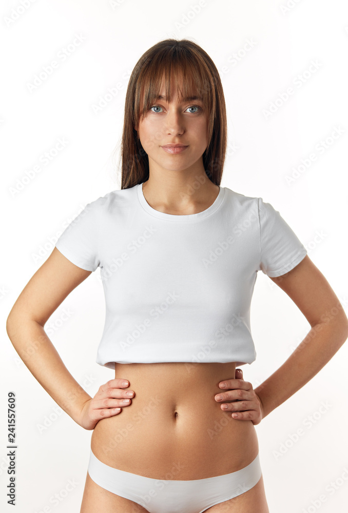 Attractive caucasian woman in white underwear demonstrates her flat belly, isolated over white background. Model of sports, dieting, fitness or plastic surgery and aesthetic cosmetology Attractive caucasian woman in white underwear demonstrates her flat belly, isolated over white background. Model of sports, dieting, fitness or plastic surgery and aesthetic cosmetology