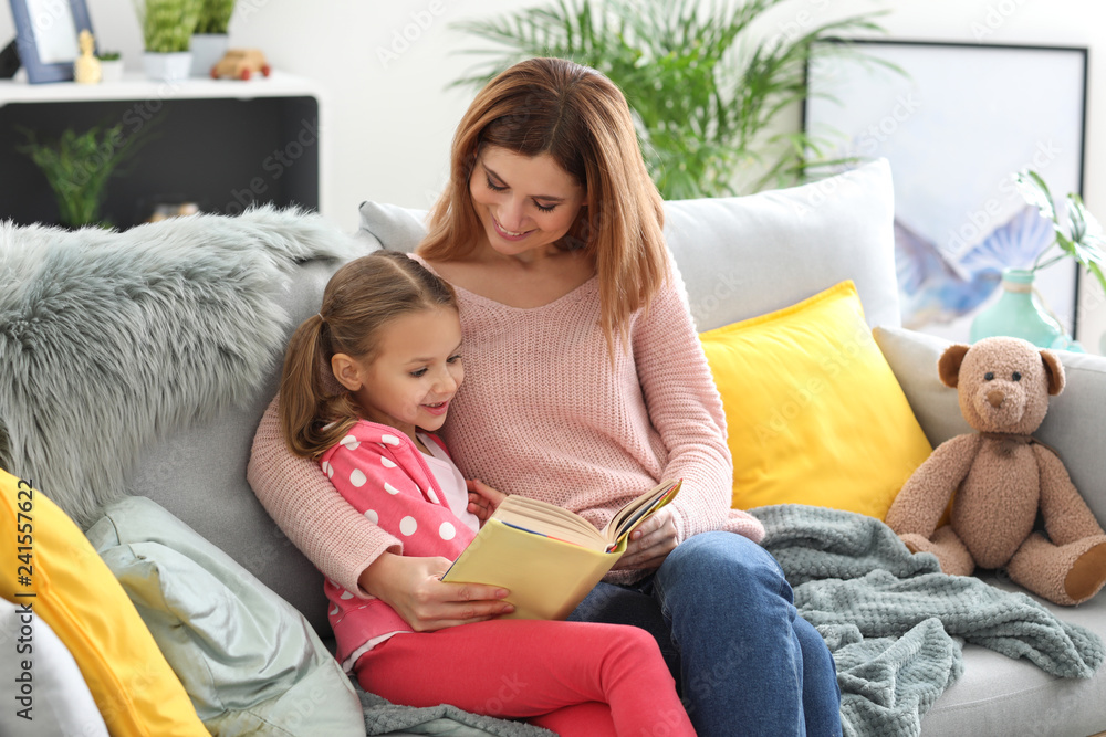 Happy mother with daughter reading book at home