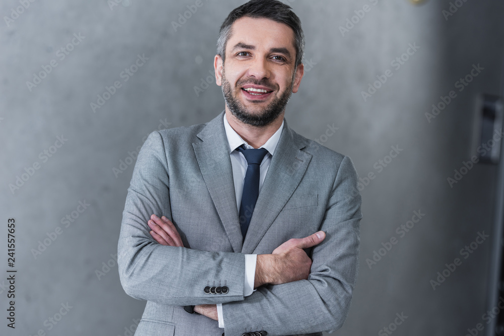 confident handsome businessman standing with crossed arms and smiling at camera confident handsome businessman standing with crossed arms and smiling at camera
