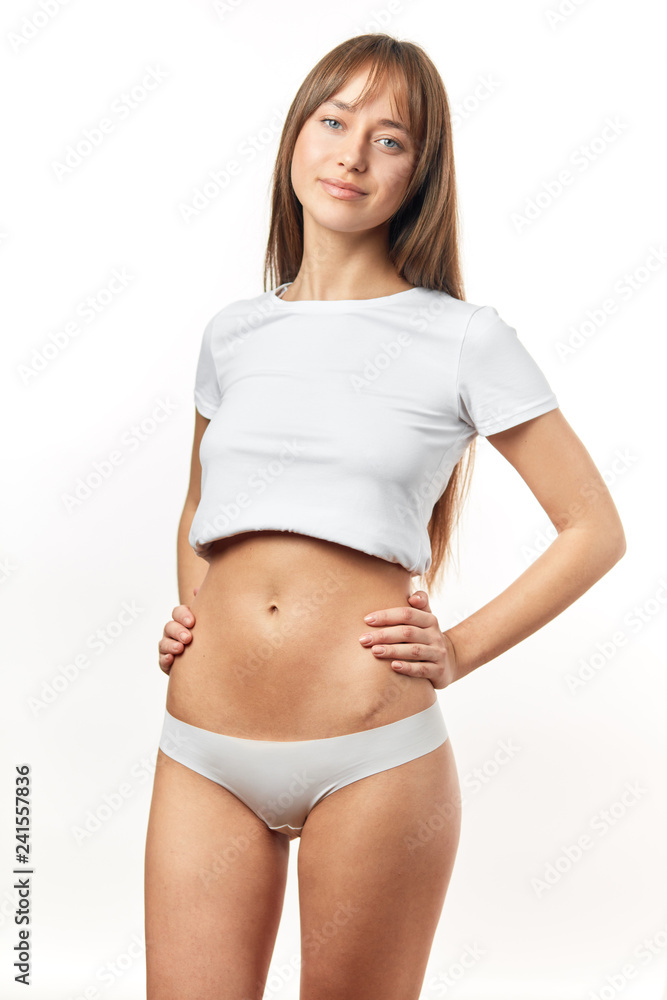 Beautiful young woman dressed in white top and panties shows her slim body and flat tummy. Girl With Perfect Body Shape, Flat Belly In Underwear. Health, Hygiene Concepts. Beautiful young woman dressed in white top and panties shows her slim body and flat tummy. Girl With Perfect Body Shape, Flat Belly In Underwear. Health, Hygiene Concepts.