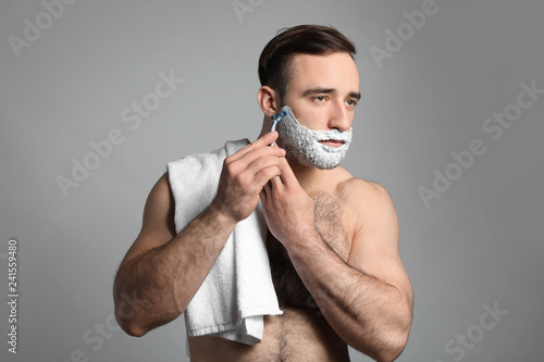 Handsome man shaving agains...