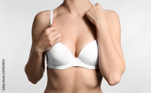 Young woman with beautiful breast on light background