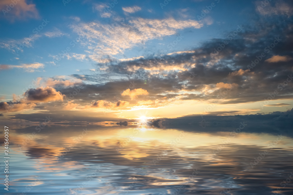 Obraz premium Wspaniały jasny zachód słońca nad spokojną powierzchnią morza.