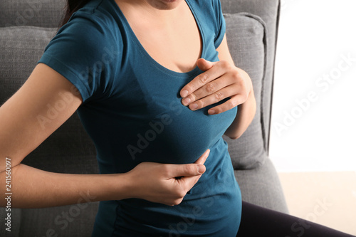 Pregnant woman touching her breast at home