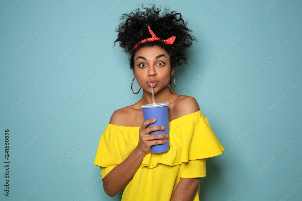 Portrait of young African-American woman with drink on color background