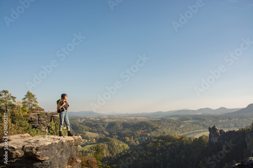 Young woman traveler with baclpack stand on the cliff in mountains © serejkakovalev