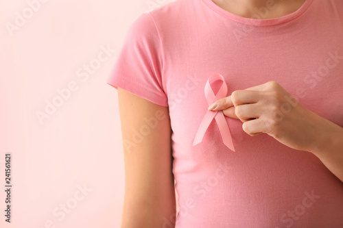 Woman with pink ribbon on color background. Breast cancer awareness concept photo