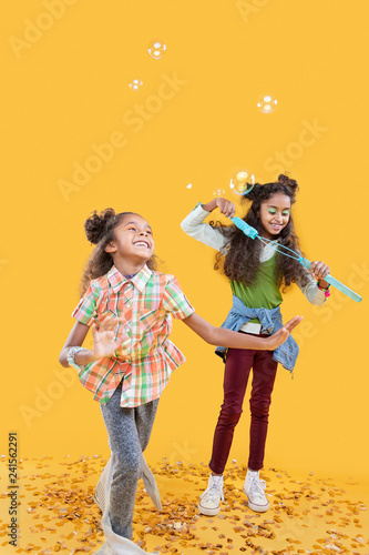 Delighted happy girls playing with soap bubbles