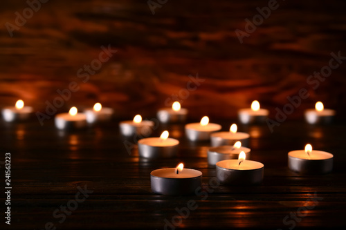 Many burning candles on table in darkness
