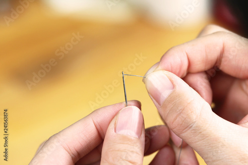 裁縫の針に糸を通している女性の手 photo
