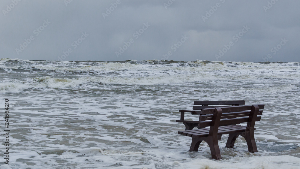 STORM AT SEA - A bench flooded by storm waves on a sea beach in Kolobrzeg 