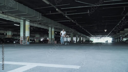 Wallpaper Mural The guy and the girl have fun in the parking lot. The man rolls the girl in the trolley from the supermarket in the underground parking Torontodigital.ca