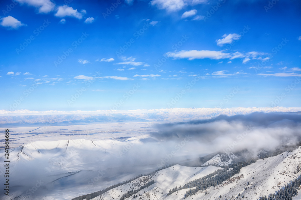 Scenic alpine landscape with fog under mountains, forest and blue sky. National park of Kyrgyzstan. Nice view. Scenic alpine landscape with fog under mountains, forest and blue sky. National park of Kyrgyzstan. Nice view.