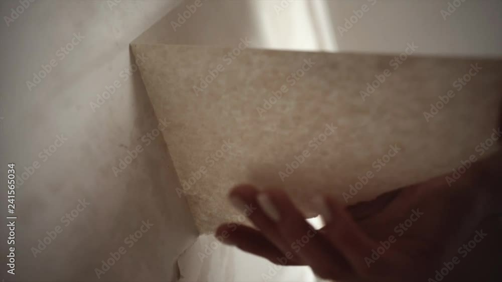 Woman hand scrapes wallpaper off walls. Removing the wallpaper in the room. Girl tears off wallpaper Woman hand scrapes wallpaper off walls. Removing the wallpaper in the room. Girl tears off wallpaper