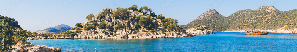 Panorama view of Tourist cruise near small rocky island in Ufakdere, Kas, Antalya, Mediterranean coast of Turkey