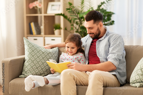 family, leisure and people concept - happy father and daughter reading book at home