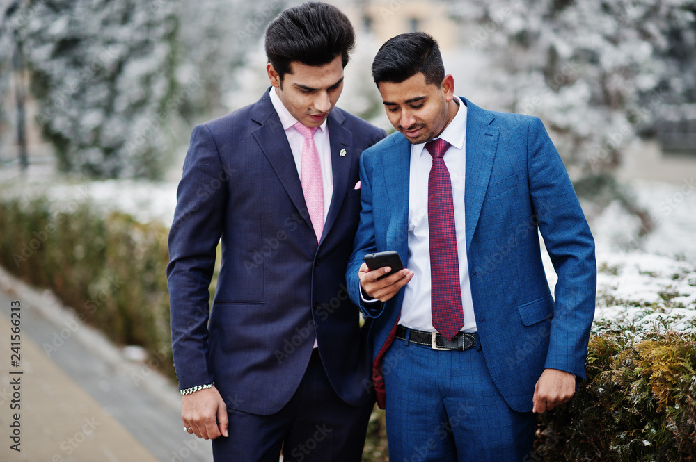 Two elegant indian fashionable mans model on suit posed at winter day looking at phone. Two elegant indian fashionable mans model on suit posed at winter day looking at phone.
