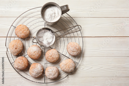 Cooling rack with tasty cookies and sugar powder on light table