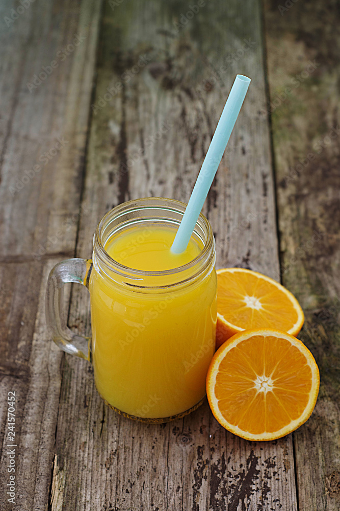 Fototapeta premium Fresh orange juice in the mason jar on wood table, rustic wooden table. Vertical image.