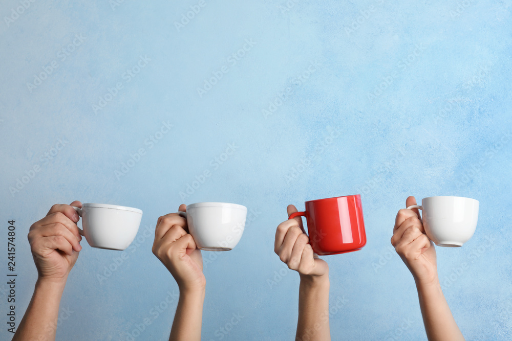 Woman holding different cup from others on color background - obrazy, fototapety, plakaty 