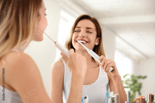 Fototapeta Naklejka Na Ścianę i Meble -  Young beautiful woman with toothbrush near mirror in bathroom. Personal hygiene