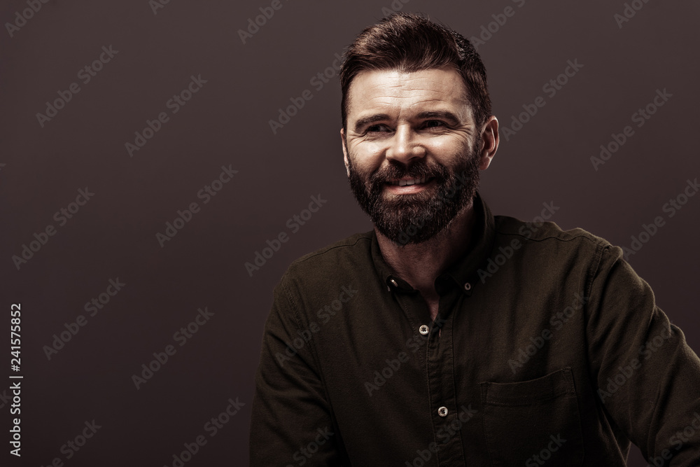 Obraz premium handsome bearded man in brown shirt smiling isolated on brown