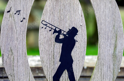 Obraz na plátne Trombonist design on a garden bench
