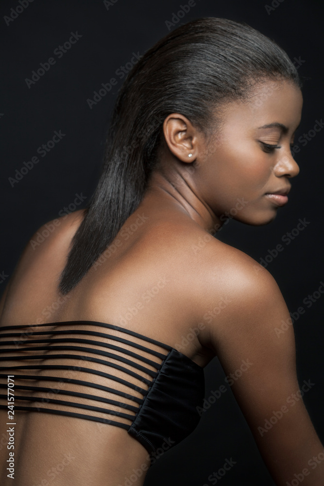 Profile of a beautiful, young, black woman wearing a sexy, black bikini top  with her eyes close. Stock Photo | Adobe Stock
