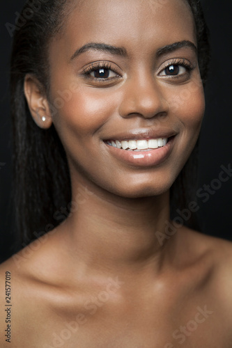 Portrait of a beautiful, young, black woman with a big smile and glowing skin.