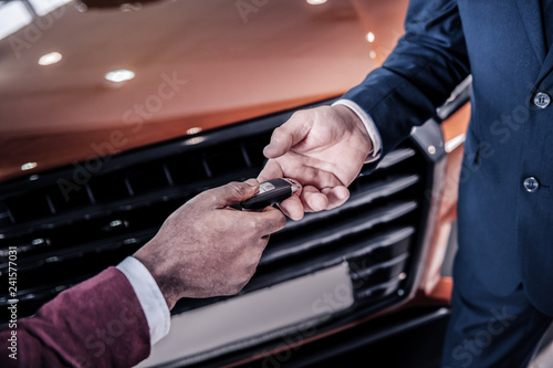 Rich successful man taking keys from his new car from sales manager