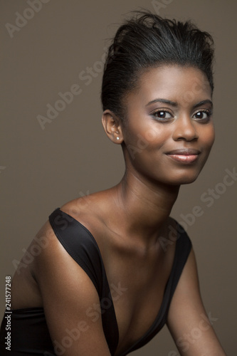 Portrait of a young, beautiful, black woman wearing a black, modern swimsuit with a soft smile.