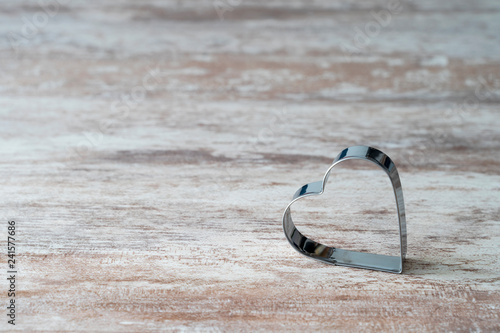 Cozy wooden background, with a heart-shaped kitchen mold on the bottom, love concept, for Valentine's Day, Mother's Day, Father's Day, Christmas, holidays.