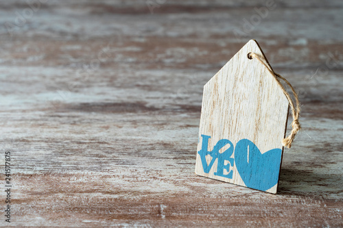Cozy wooden background, with a piece of wood in the shape of a house, a heart and the word written love, love concept, for Valentine's Day, Mother's Day, Father's Day, Christmas, holidays.