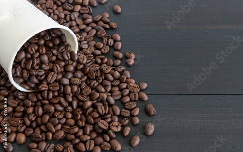 white paper cup and coffee beans on old wooden with soft-focus and over light in the background