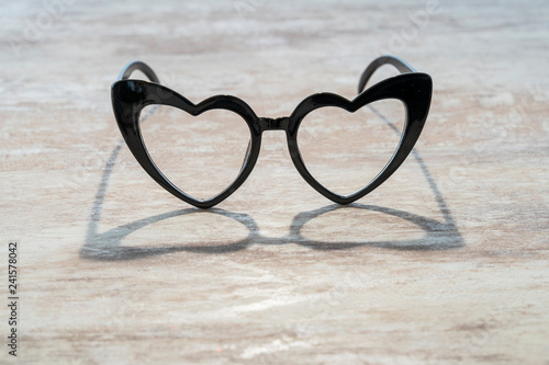 Cozy wooden background, with a heart-shaped glasses that is reflected in the wood, love concept, for Valentine's Day, Mother's Day, Father's Day, Christmas, holidays.