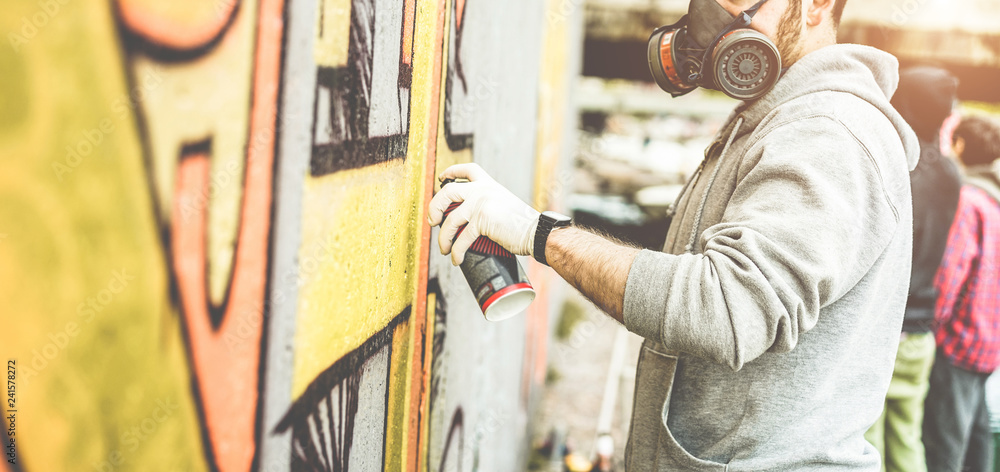 Fototapeta premium Malowanie artystów graffiti z kolorowym sprayem na ścianie w międzynarodowym konkursie - Urban, street art, pokolenie milenium, koncepcja muralu - Skup się na dłoni