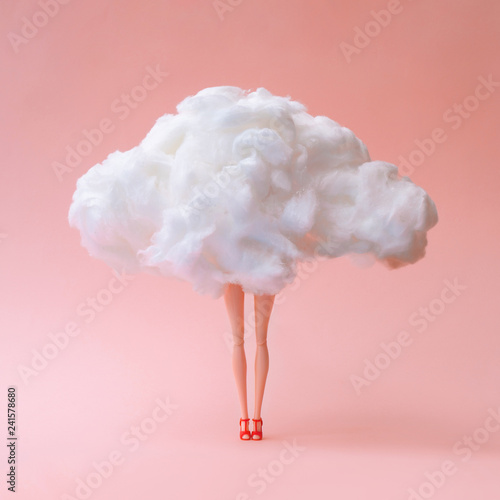 Girl doll against pastel coral color background. Head in the clouds concept.