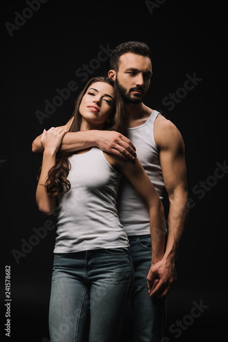 sexual man hugging attractive woman in white singlet isolated on black