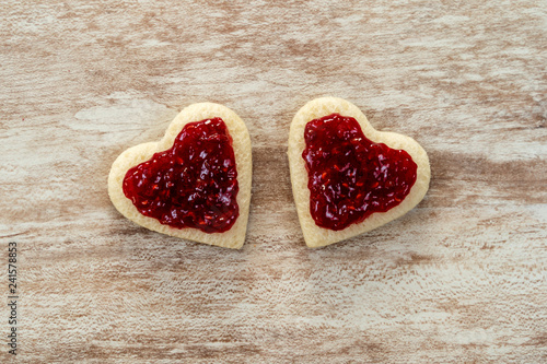  2 heart-shaped sandwich bread in a corner, with strawberry jam on a cozy wooden background, love concept, for Valentine's Day, Mother's Day, Father's Day, Christmas, holidays.